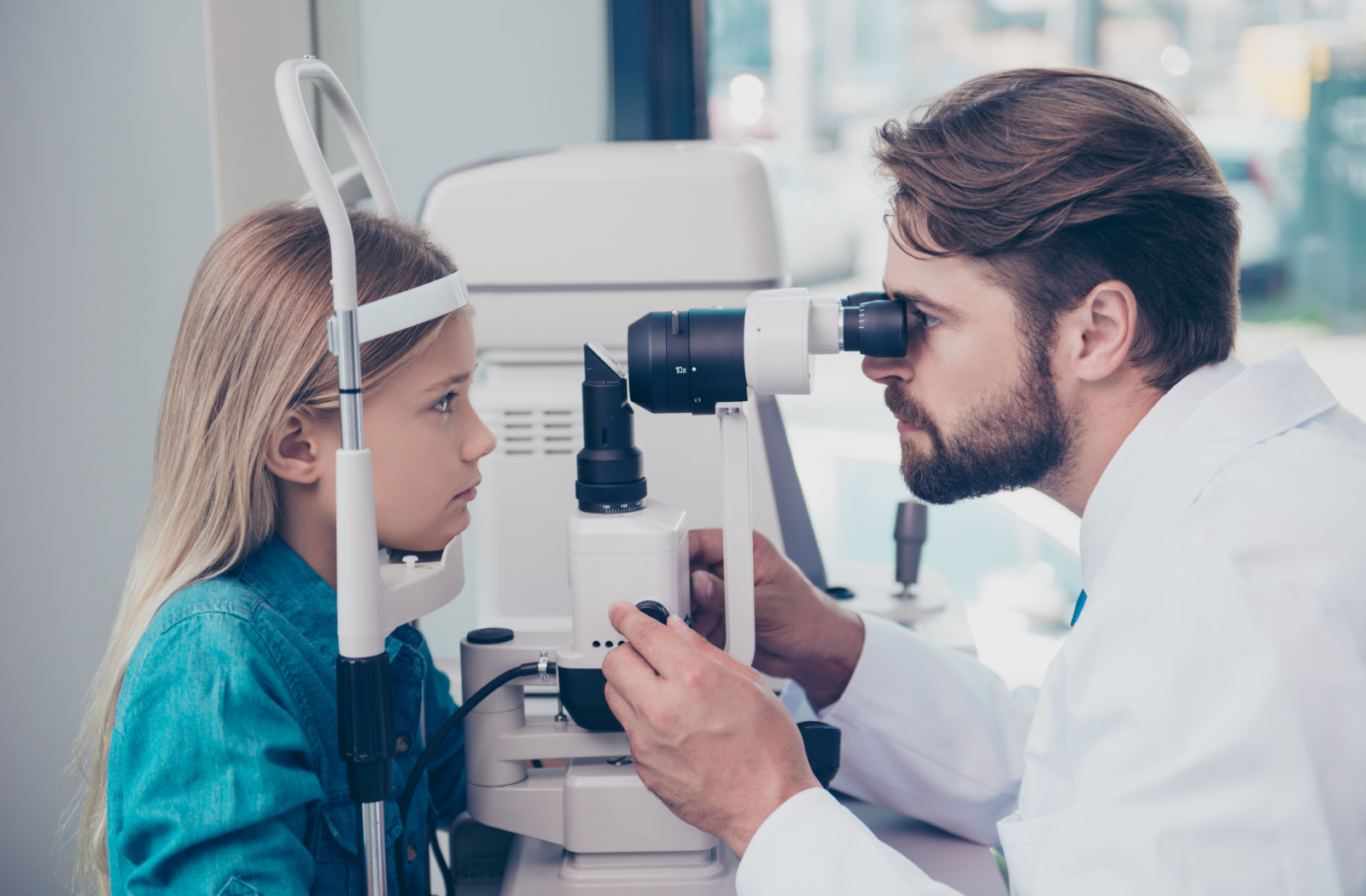 An optometrist performs a slit-lamp exam on a child to detect eye conditions and diseases.
