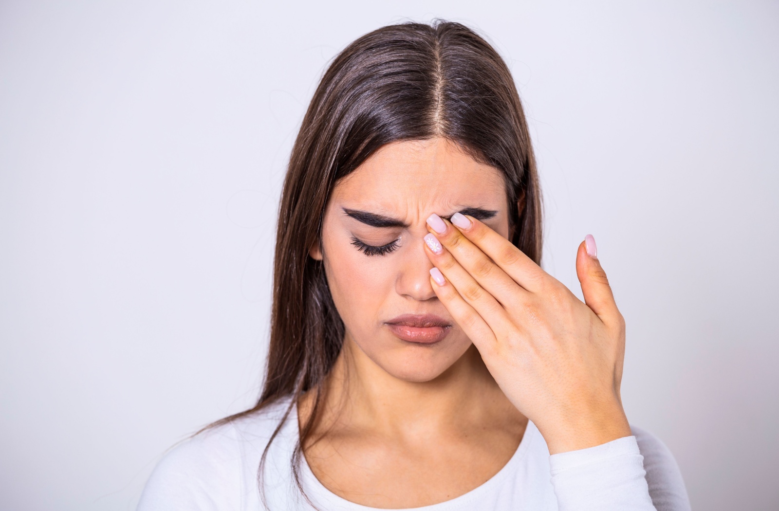 A woman rubbing her left eye with her left hand
