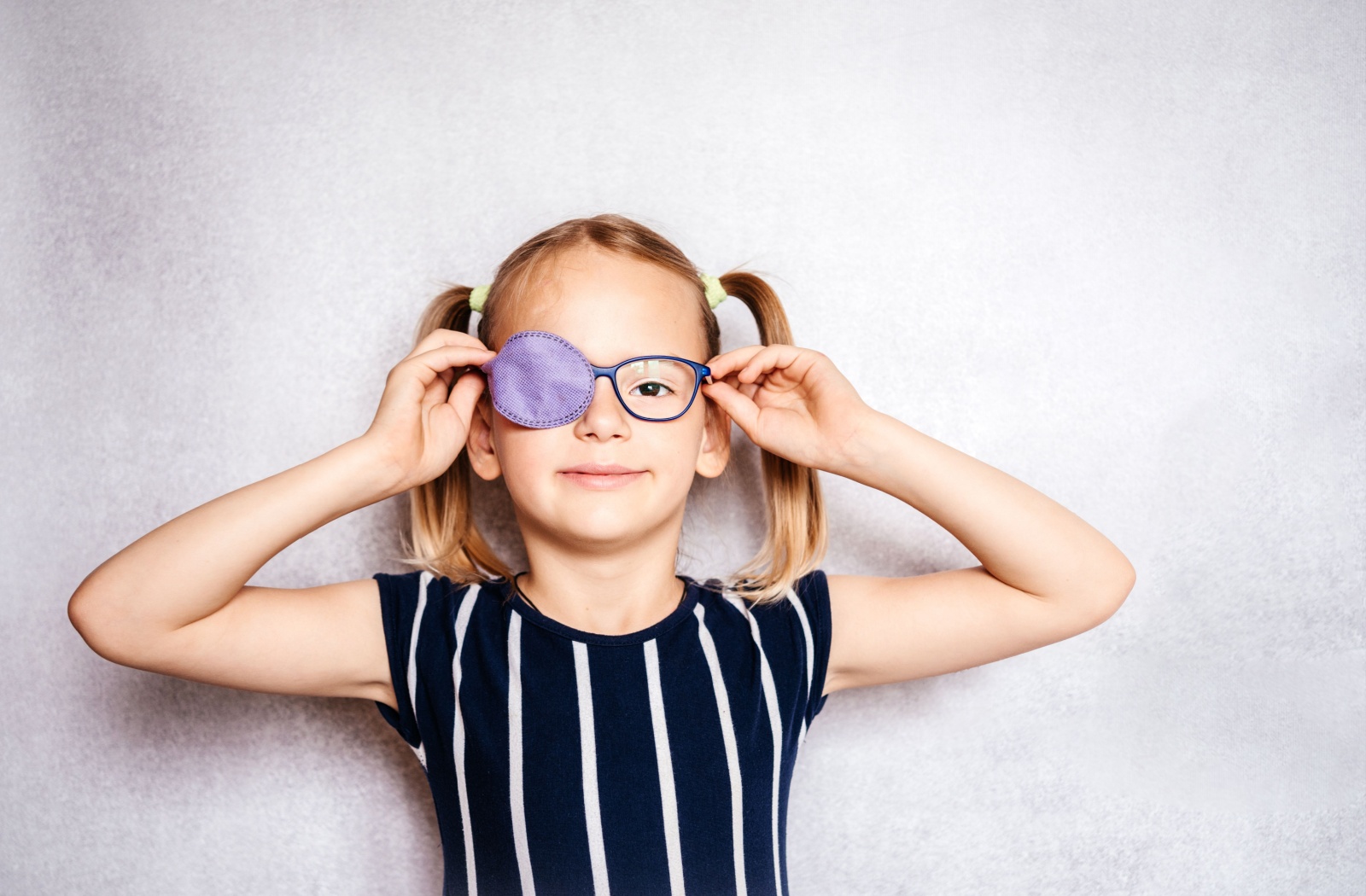 A young child with amblyopia puts on glasses that have a patch over 1 lens.
