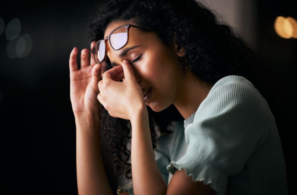 Person rubbing their eyes from eye strain, with their glasses pushed up to their forehead.