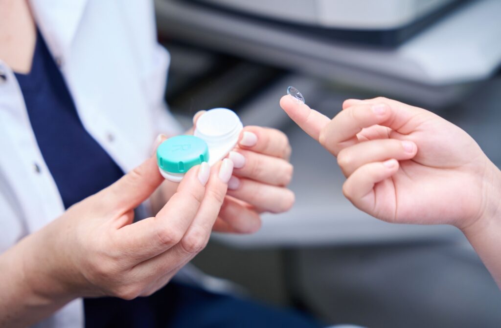 Optometrist handing contact lenses to a patient during an eye exam.