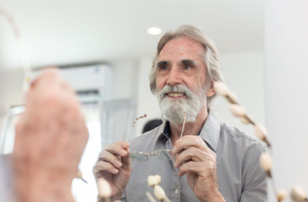 Older adult taking off glasses in the mirror.