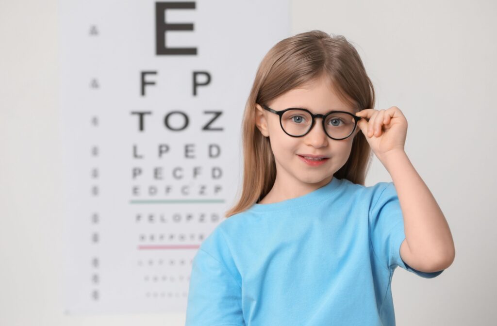 A child wearing glasses in front of an eye test chart