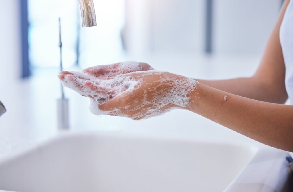 A person cleaning their hands at the sink before using contact lenses
