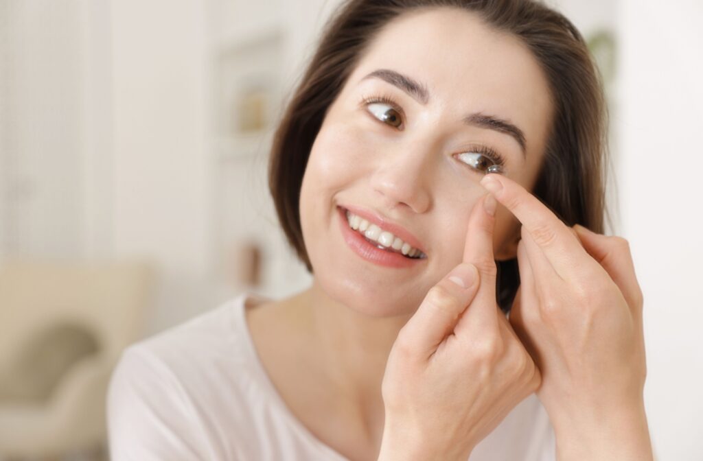 A person looking in the mirror as they put a contact lens in their eye while struggling with dry eye