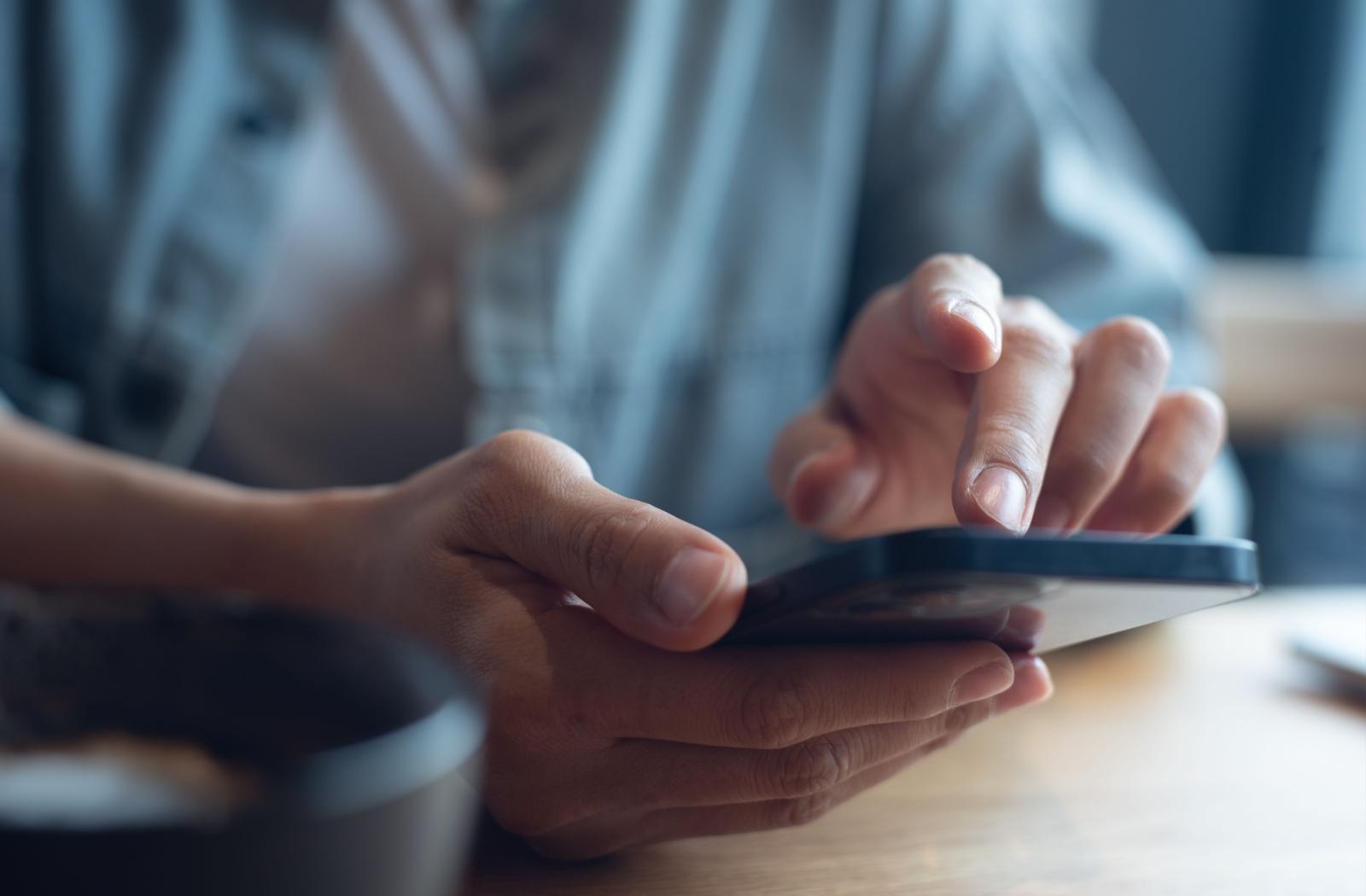 A close up of hands holding a phone that is being used